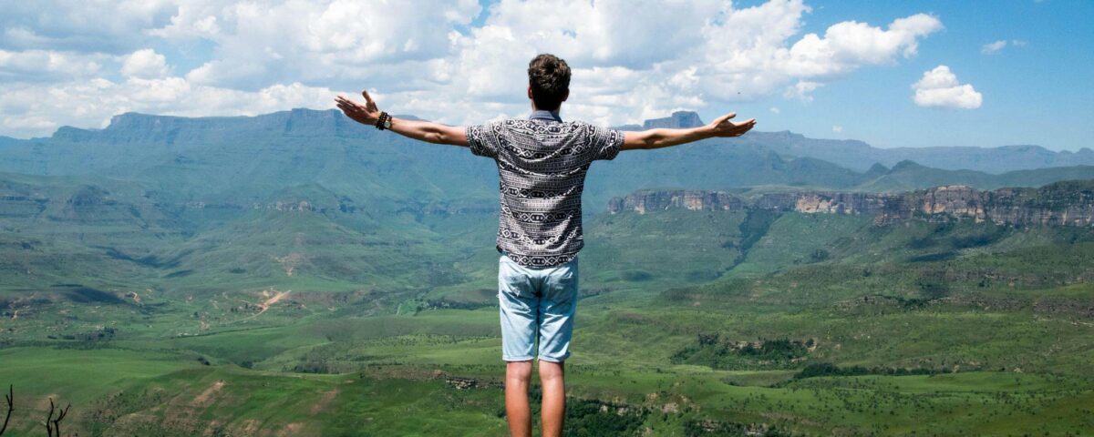 muz-s-roztiahnutymi-rukami-na-kopci-nad-krajinou